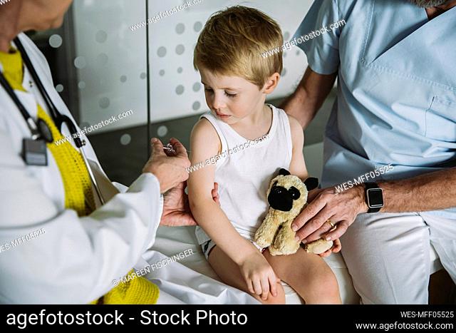 Pediatrist injecting vaccine into arm of toddler
