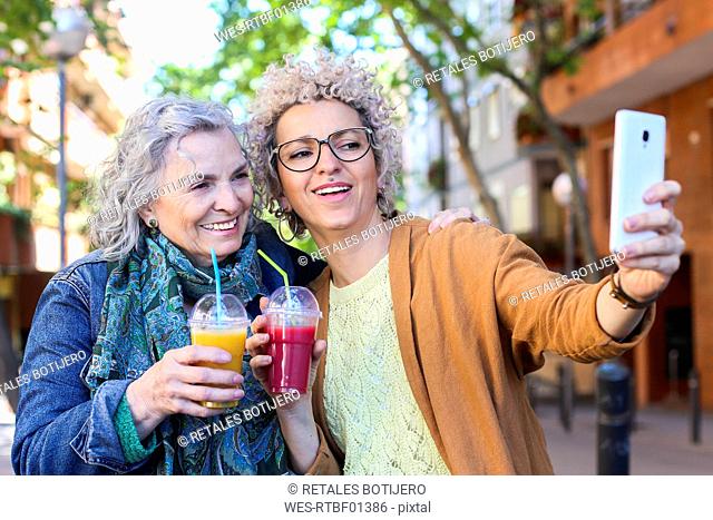 Senior mother with her adult daughter taking selfie in the city
