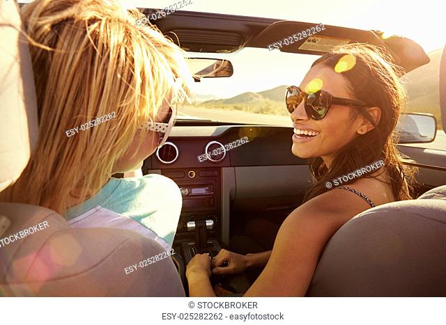 Two Female Friends On Road Trip Driving In Convertible Car