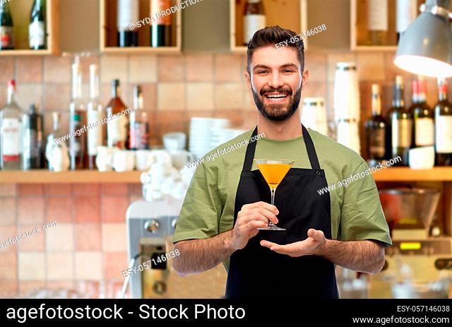 barman in apron with glass of cocktail at bar