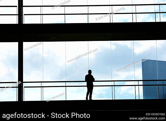 Silhouette view of young businessman in a modern office building interior with panoramic windows