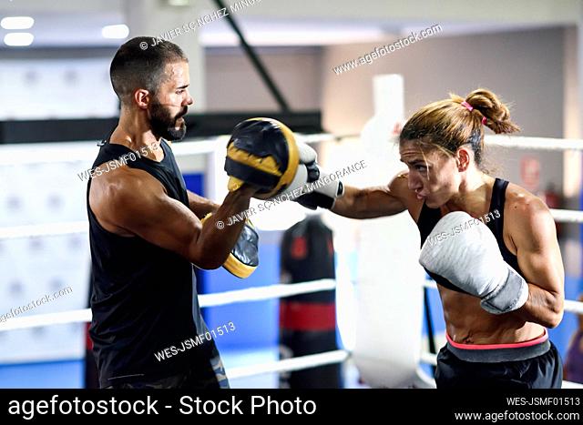 Female boxer sparring with her coach in gym