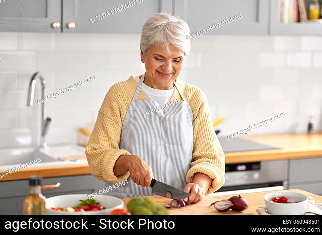 happy woman chopping red onion on kitchen