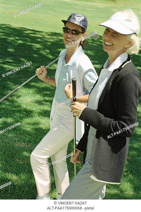 Two mature women with golf clubs, portrait