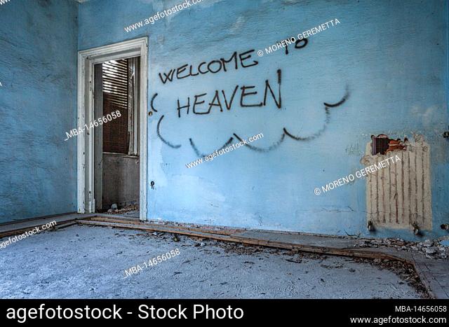 Italy, Veneto, dusty room of an abandoned house, welcome to heaven written on the wall