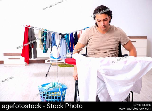 The young man in wheel-chair doing ironing at home