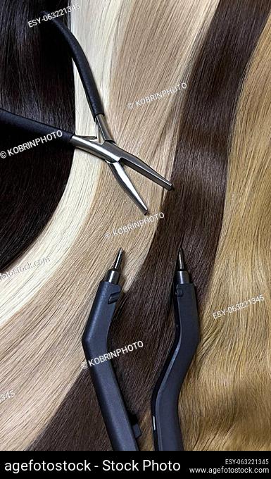 Strands of natural hair in different colors for extensions with tools. Hair color palette. Close-up
