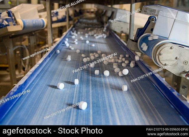 12 July 2021, Saxony-Anhalt, Staßfurt: In the new plant of the chemical company Ciech, produced salt tablets fall onto a conveyor belt