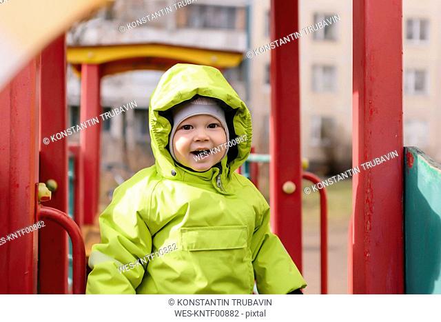 Portrait of happy toddler with rain jacket on playground