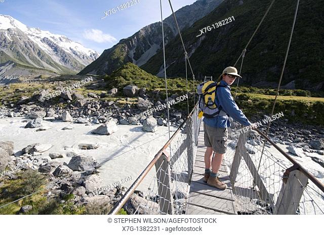 A hiker crossing the first Hooker Valley swingbridge, en route for the glacier lake, South Island of New Zealand