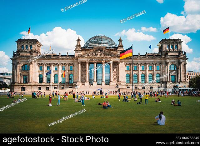 Berlin, Germany - August, 2019: Many people on meadow in front of the Reichstag building (German Bundestag), a famous landmark on a sunny, summer day in Berlin