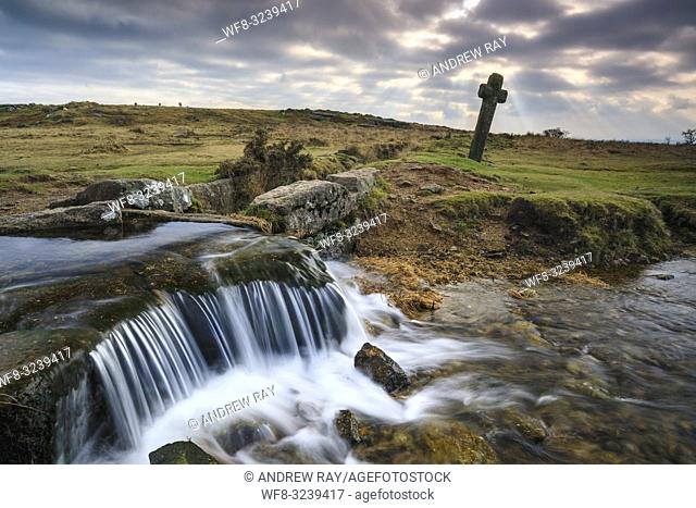 The Celtic cross and waterfall at Windy Post in the Dartmoor National Park. The image was captured on an atmospheric afternoon in mid January