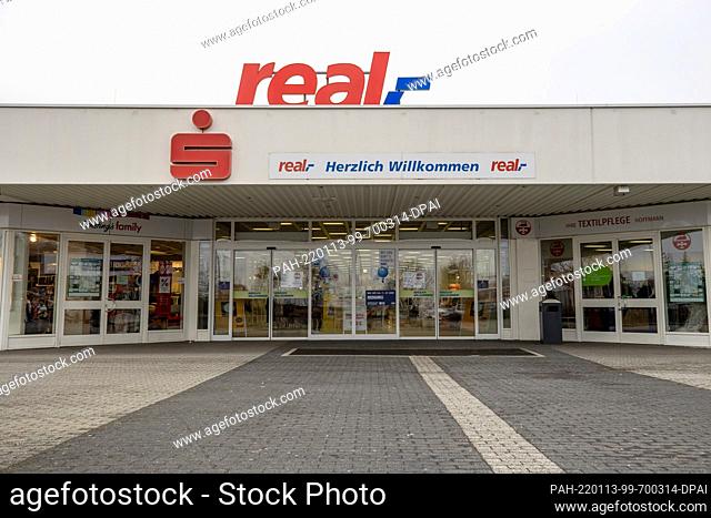 11 January 2022, Saxony, Heidenau: Under the logo of the supermarket chain real, - hangs a sign ""Welcome"" and an ""S"" of the Sparkasse