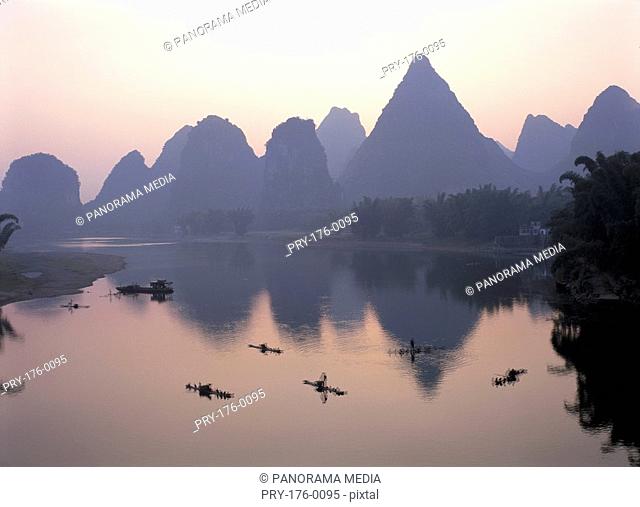 Fishermen on boat and distant mountain-range, Li River, Yangshuo, Guilin