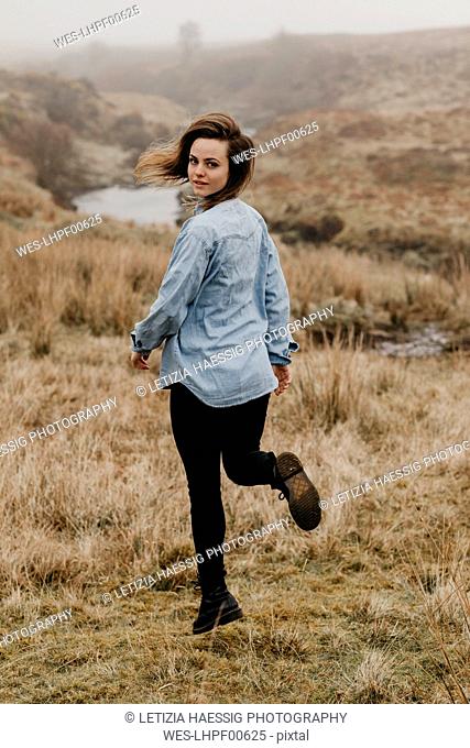 UK, Scotland, Isle of Skye, young woman running in rural landscape