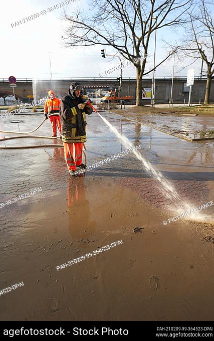09 February 2021, Rhineland-Palatinate, Vallendar: Employees of the municipal building yard clean the Bundesstraße 42 from the mud that remained there after the...