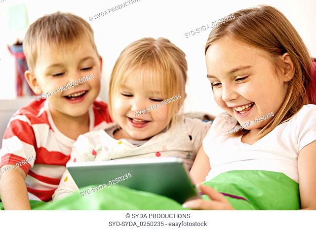happy little kids with tablet pc in bed at home
