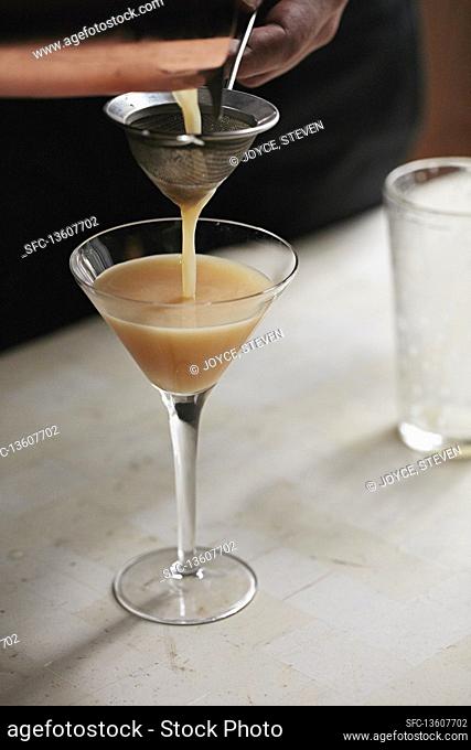 A whisky sour cocktail being poured