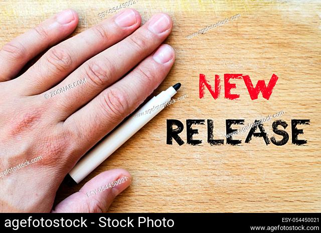 Human hand over wooden background and new release text concept