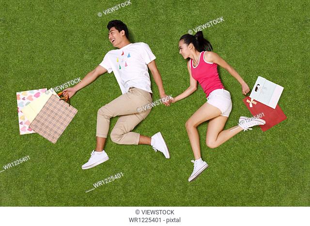 Young couple holding shopping bags on grass
