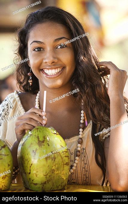 Smiling teenage girl drinking from coconut