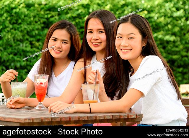 Portrait of three young beautiful Asian women as friends together relaxing at the coffee shop with nature outdoors