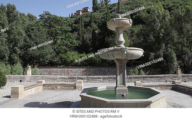 LA, TILT up, daylight, fountain in the Albaicin area and view of the Nasrid Palaces on the hill. Alhambra was declared World Heritage Site by UNESCO in 1984