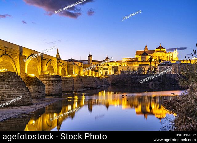 Roman bridge over Río Guadalquivir river and the Mezquita - Mosque–Cathedral of Córdoba at dusk, Andalusia, Spain
