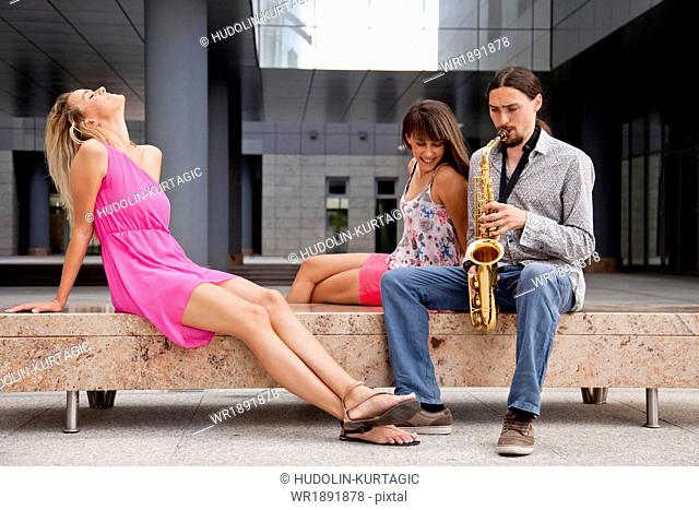 Man playing the saxophone to women, Osijek, Croatia
