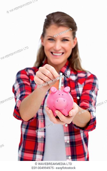 Portrait of a woman putting a note a piggy bank