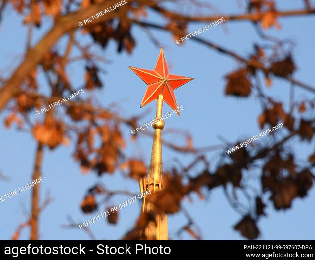 PRODUCTION - 18 November 2022, Saxony, Leipzig: At the Alte Messe, the 60-meter-high golden spire with the Red Star can be seen behind trees from a construction...