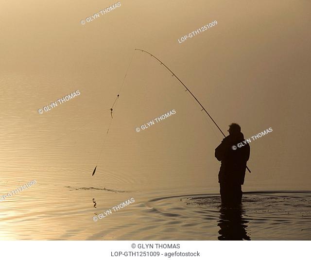 England, Cumbria, Bassenthwaite, The silhouette of a lone angler fishing in Bassenthwaite Lake in the Lake District
