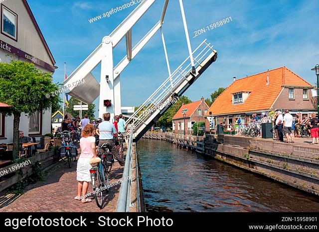 Ossenzijl, The Netherlands- September 03, 2011: Pedestrians and bikers waiting for opened bridge for yachts passing in the canal