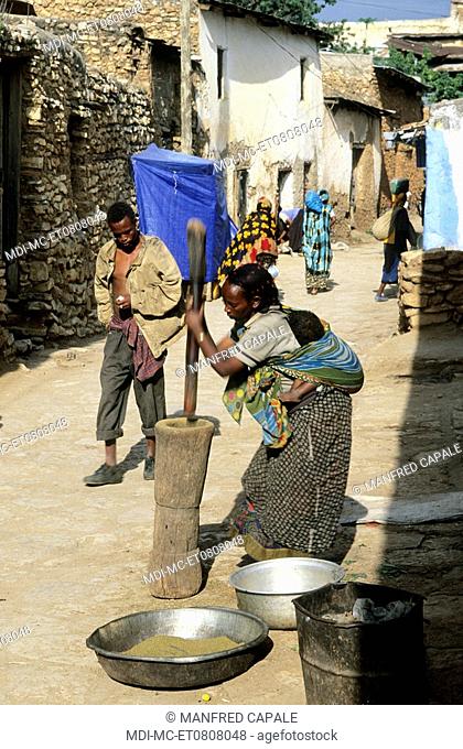 Woman with child in her back pounding cereals in the street