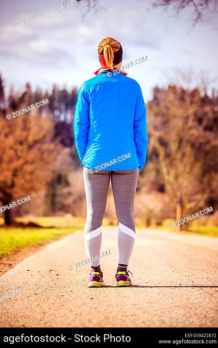 Girl in sportswear is waiting to start her training, countryside