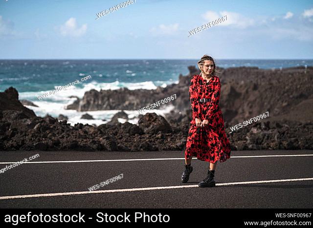 Female tourist looking away while standing on road at Los Hervideros, Lanzarote, Spain