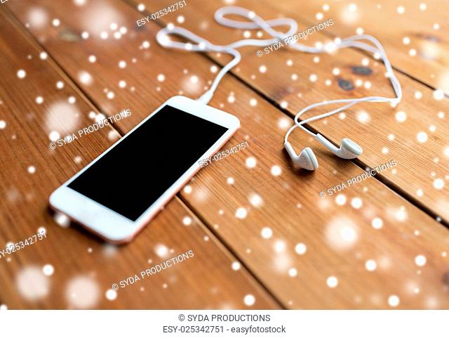 technology, music, gadget and object concept - close up of white smartphone and earphones on wooden surface with copy space