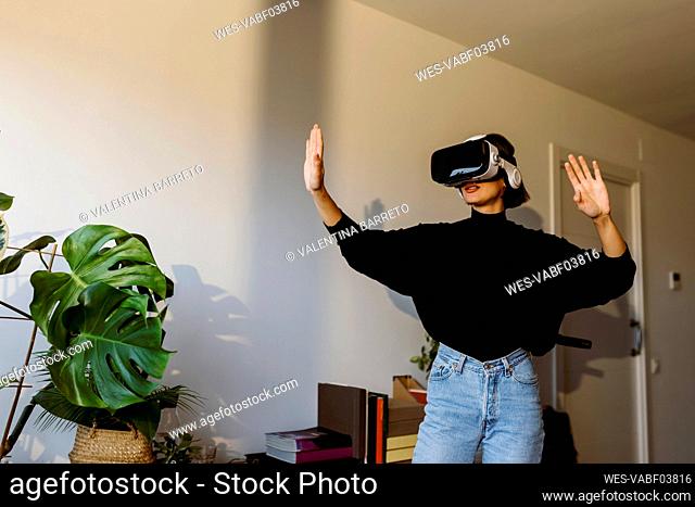 Woman wearing virtual reality simulator while standing at home