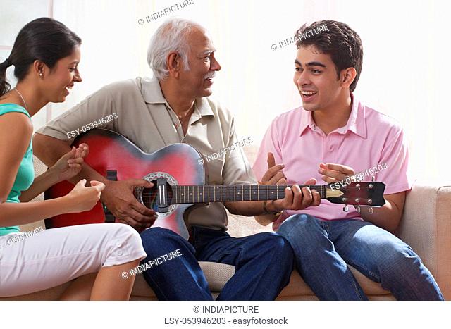 Grandfather playing the guitar and grandchildren singing