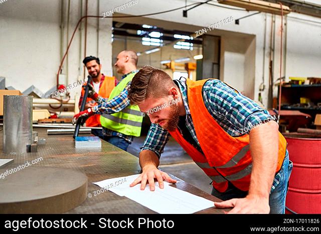 Arbeiter als Facharbeiter liest eine Bestellung in der Metallbau oder Schlosserei Werkstatt