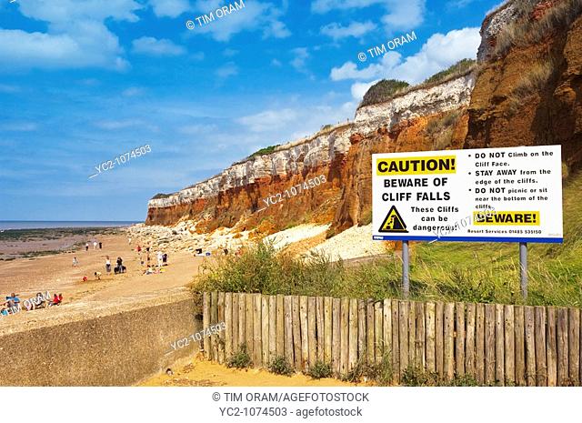 The beach and cliffs with people and warning sign at Hunstanton , North Norfolk , Uk