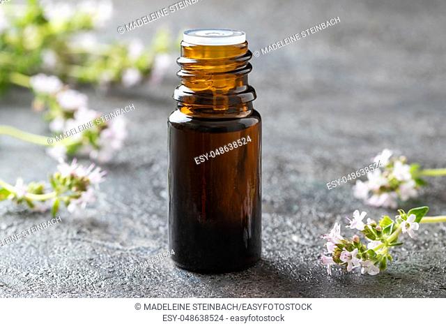 A bottle of essential oil with fresh blooming thyme