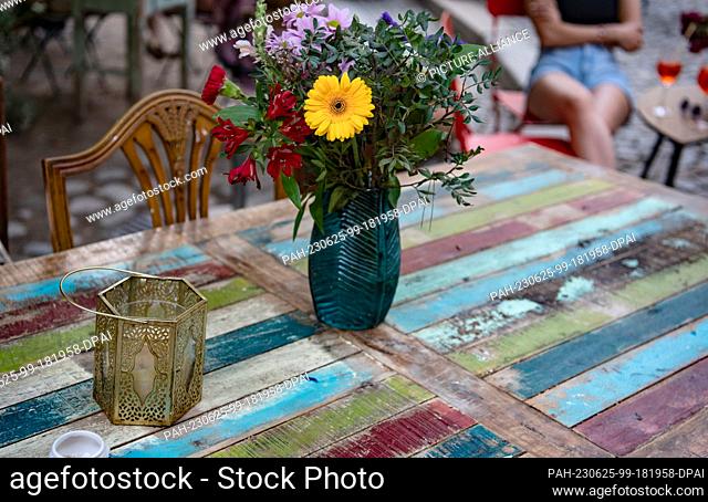 20 June 2023, Berlin: BBlowers stand in a vase on an artfully designed table in the Heckmann-Höfe in Mitte. The Heckmann-Höfe in Berlin are a structural...