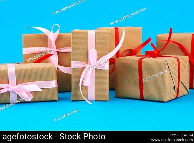 stack of boxes wrapped in brown paper and tied with a red bow, gifts on a blue background. Great design for any purposes. Holiday background