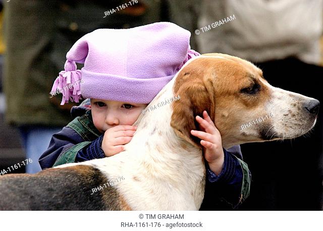 A toddler crying whilst embracing a foxhound before the Heythrop New Year's Day Hunt in the Market Place in Stow on the Wold, Oxfordshire