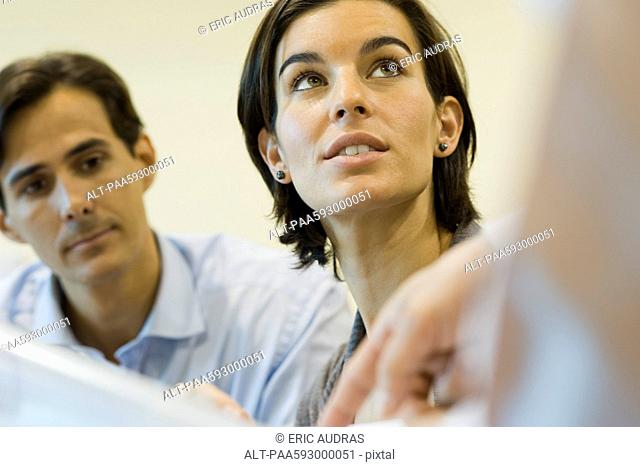 Businesswoman listening as colleague explains document, cropped