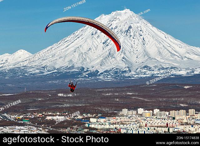 PETROPAVLOVSK-KAMCHATSKY, KAMCHATKA, RUSSIA - NOVEMBER 21, 2014: Paraglider flying over Petropavlovsk-Kamchatsky City on the background of the active Koriaksky...