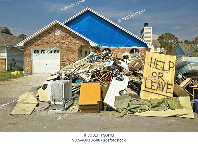 Help or Leave” sign with debris in front of house heavily hit by Hurricane Ivan in Pensacola Florida