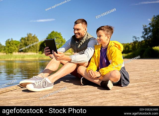 happy father and son with tablet pc on river berth
