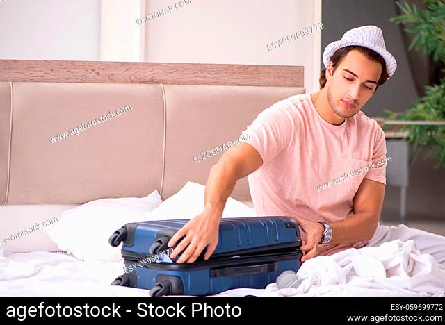 Man with suitcase in bedroom waiting for trip